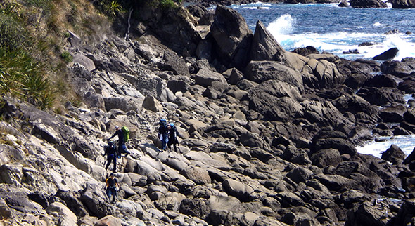 The film crew lugging their gear across the rocks